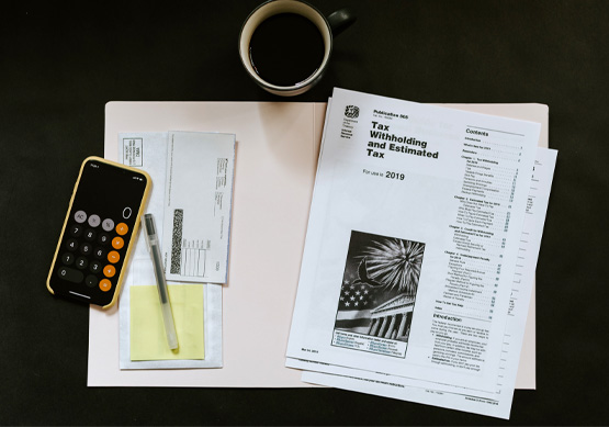 Tax filing paper work piled on a table with mobile phone calculator